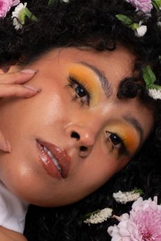 Close-up portrait of a woman with vibrant makeup surrounded by flowers.