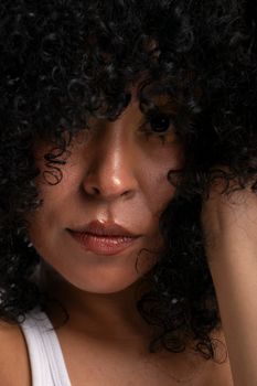 Intimate close-up portrait of a woman with curly hair and a thoughtful expression.