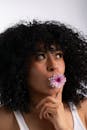 Woman with Curly Hair Holding Flower in Her Mouth