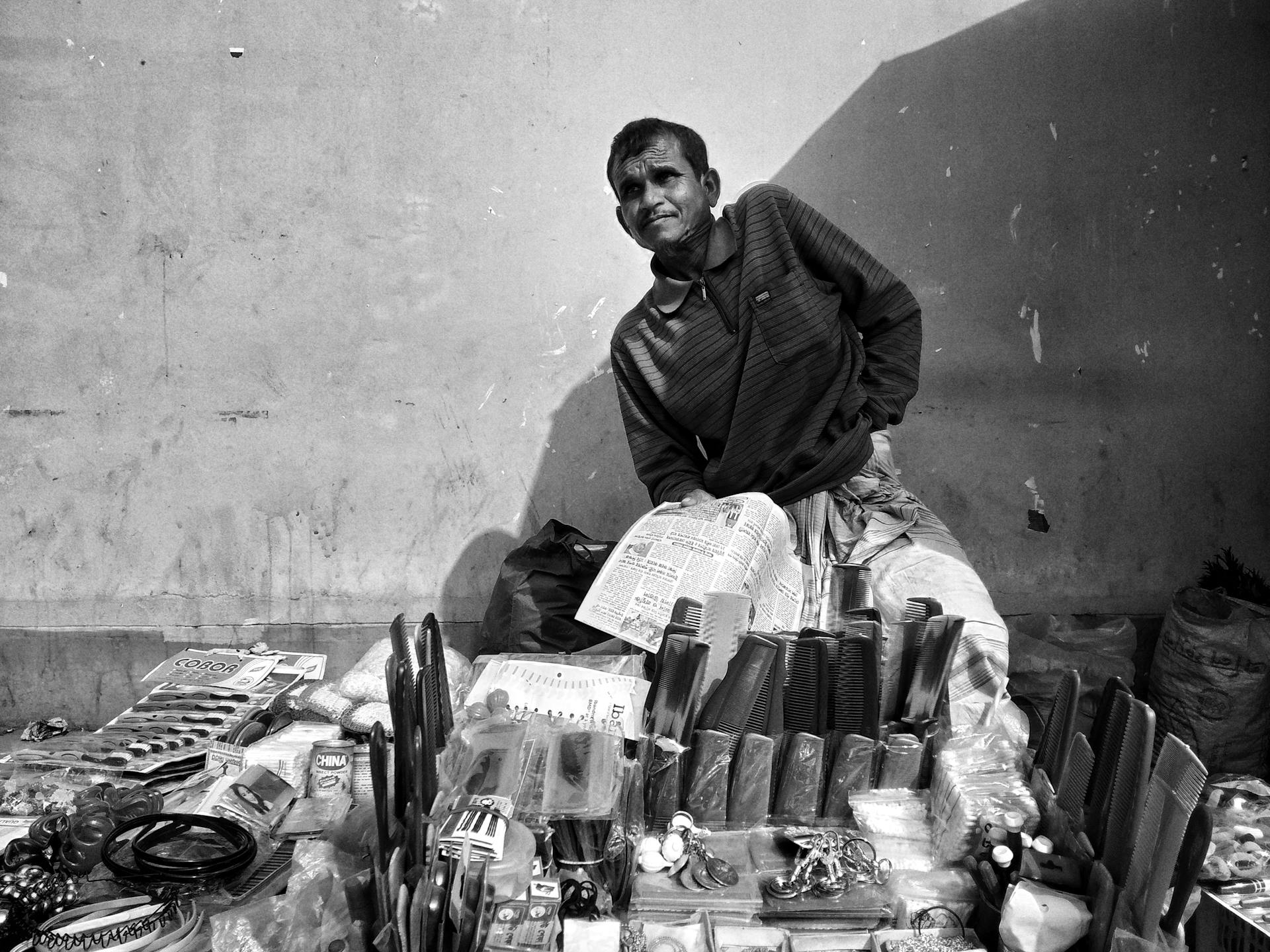 Black and white photo of a street vendor selling goods in Khulna, Bangladesh market.