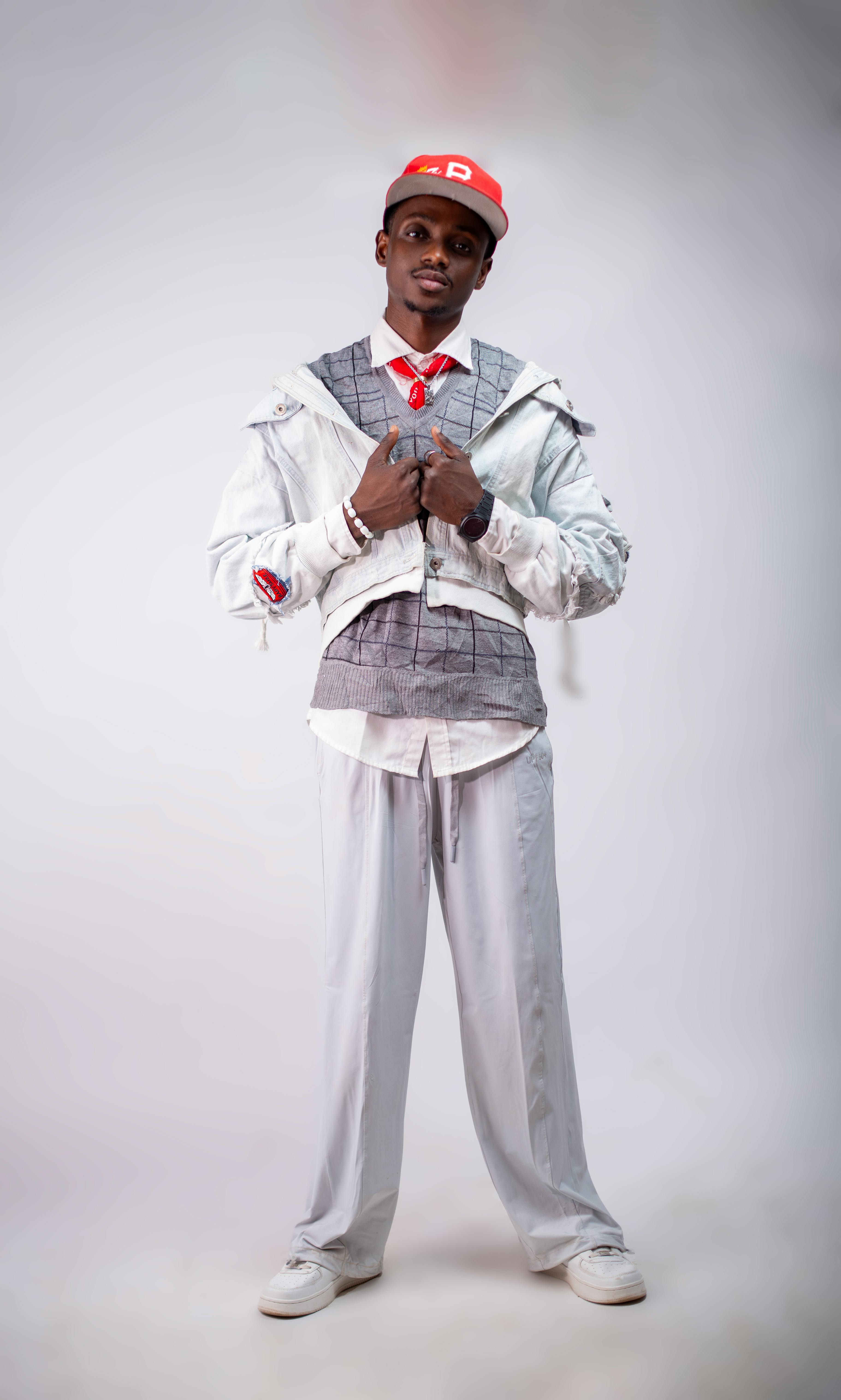 Stylish young adult in modern white outfit posing confidently indoors.