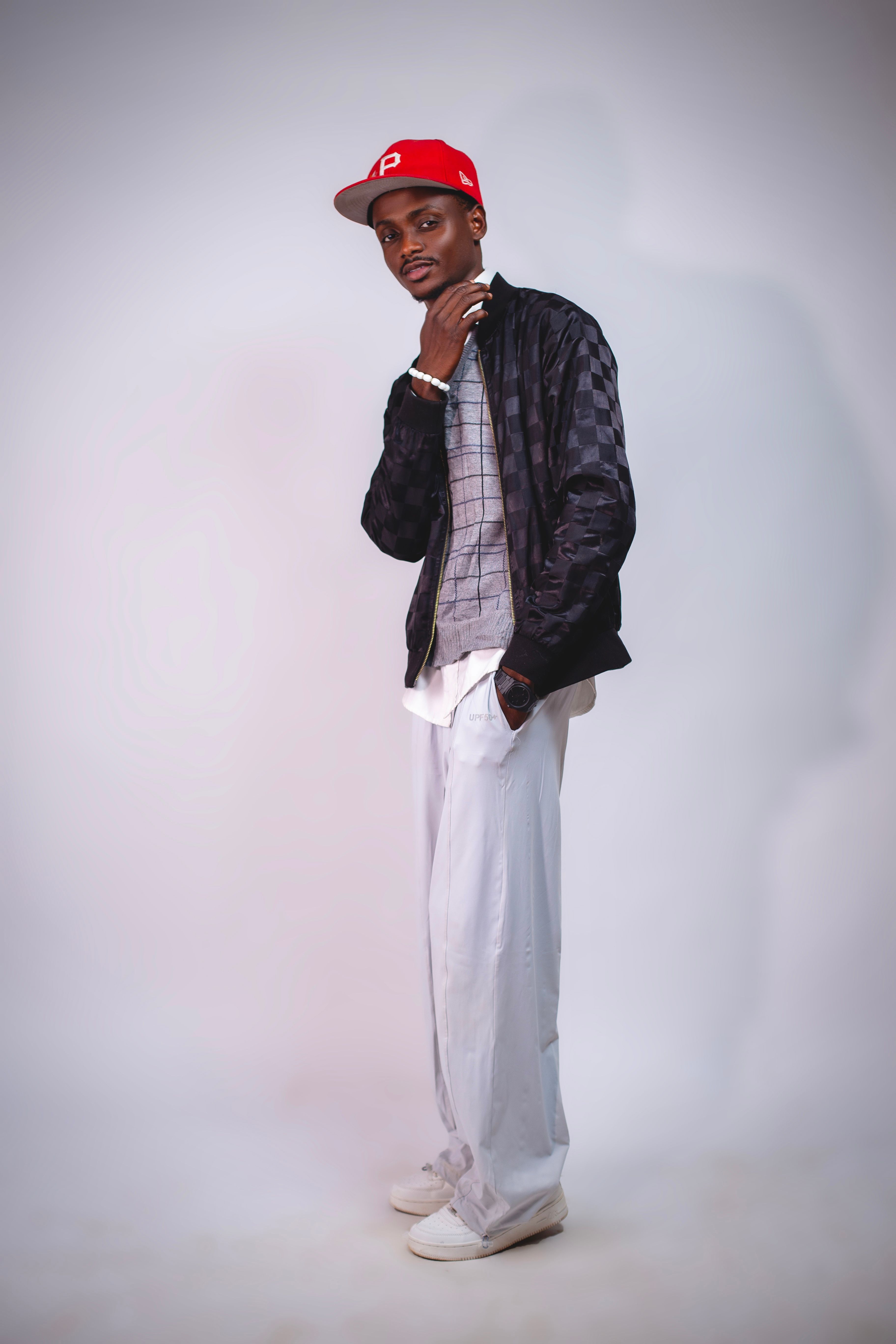 Fashionable young man posing confidently wearing a red cap and casual outfit.