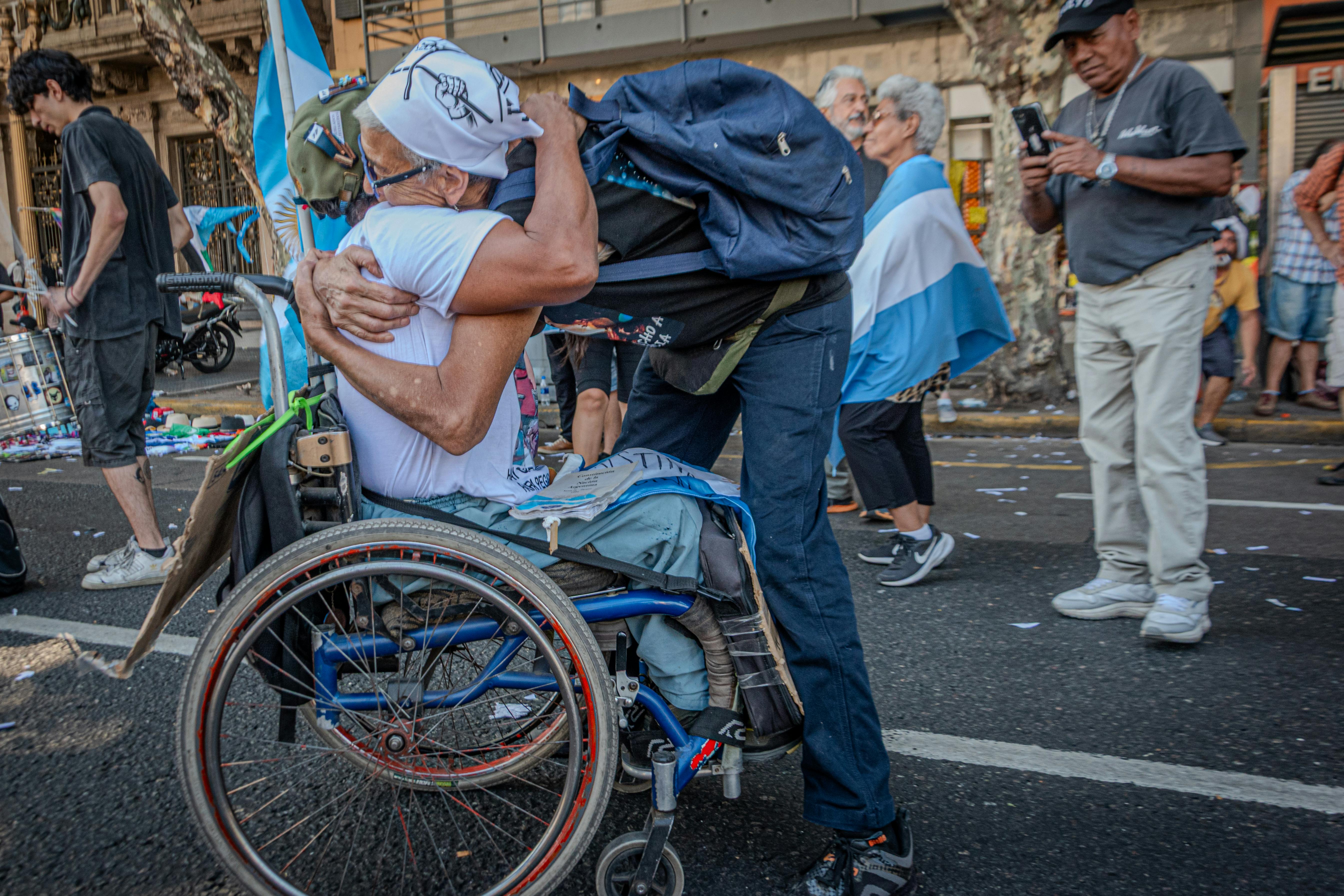 Heartfelt hug between two adults during a street protest in Buenos Aires.