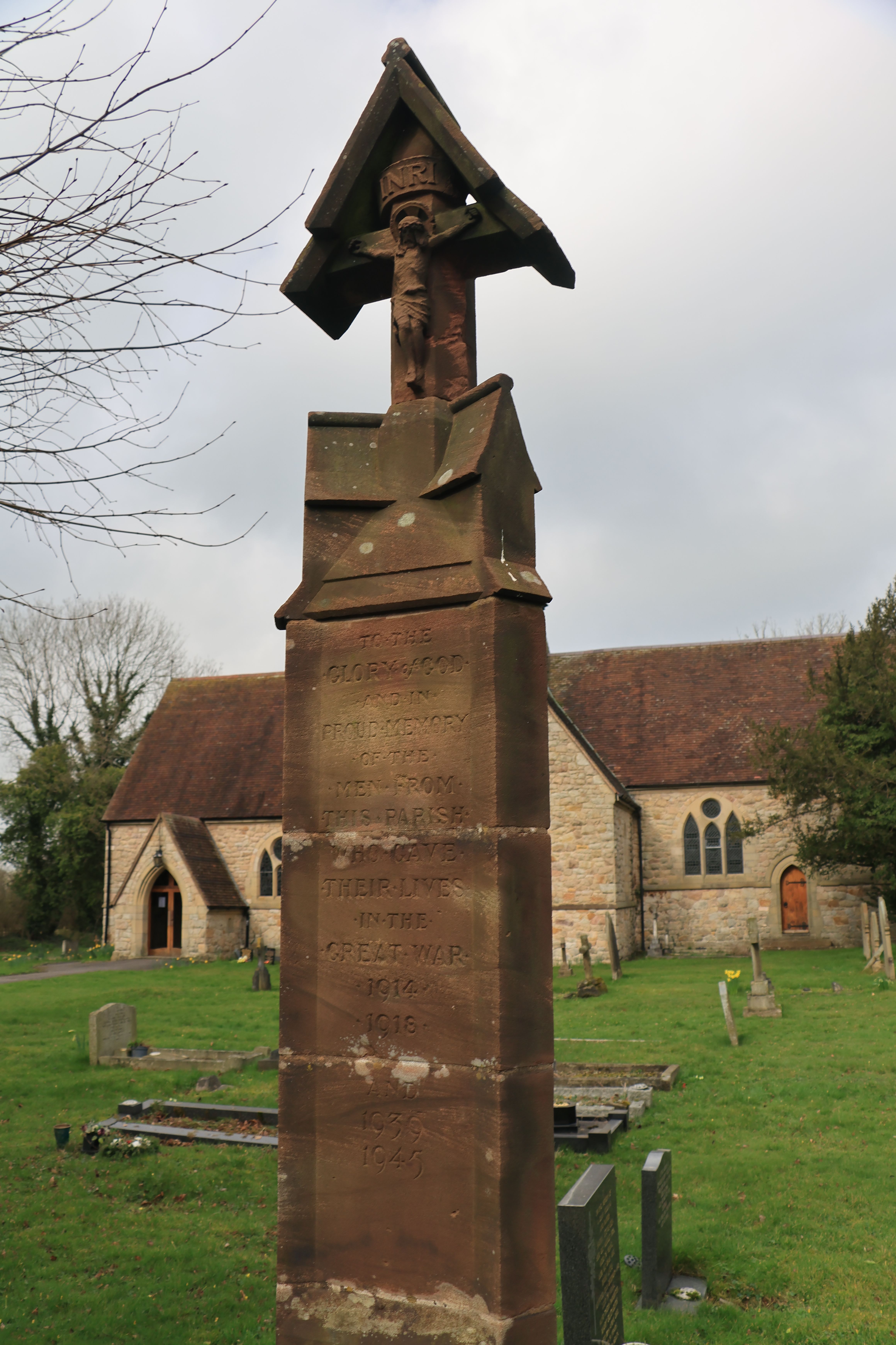 A historic monument stands in an English churchyard against a cloudy sky.