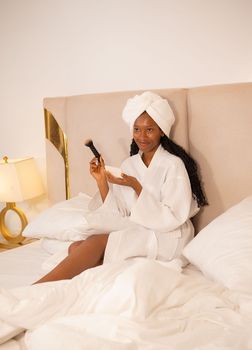 Woman enjoying a serene morning beauty routine in a cozy Abuja bedroom setting.