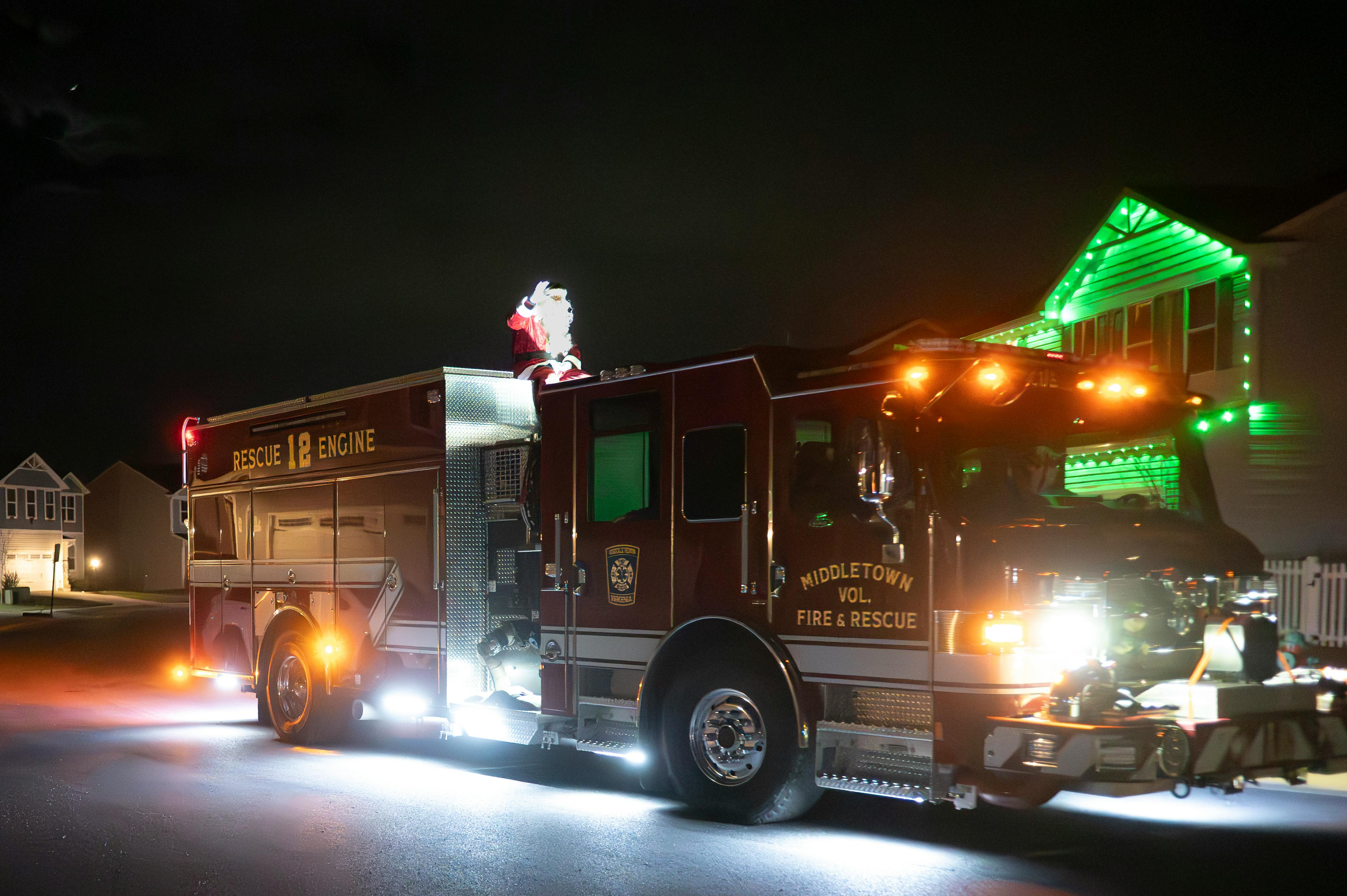 A decorated fire truck in Middletown displaying holiday cheer with Santa on top, illuminated at night.