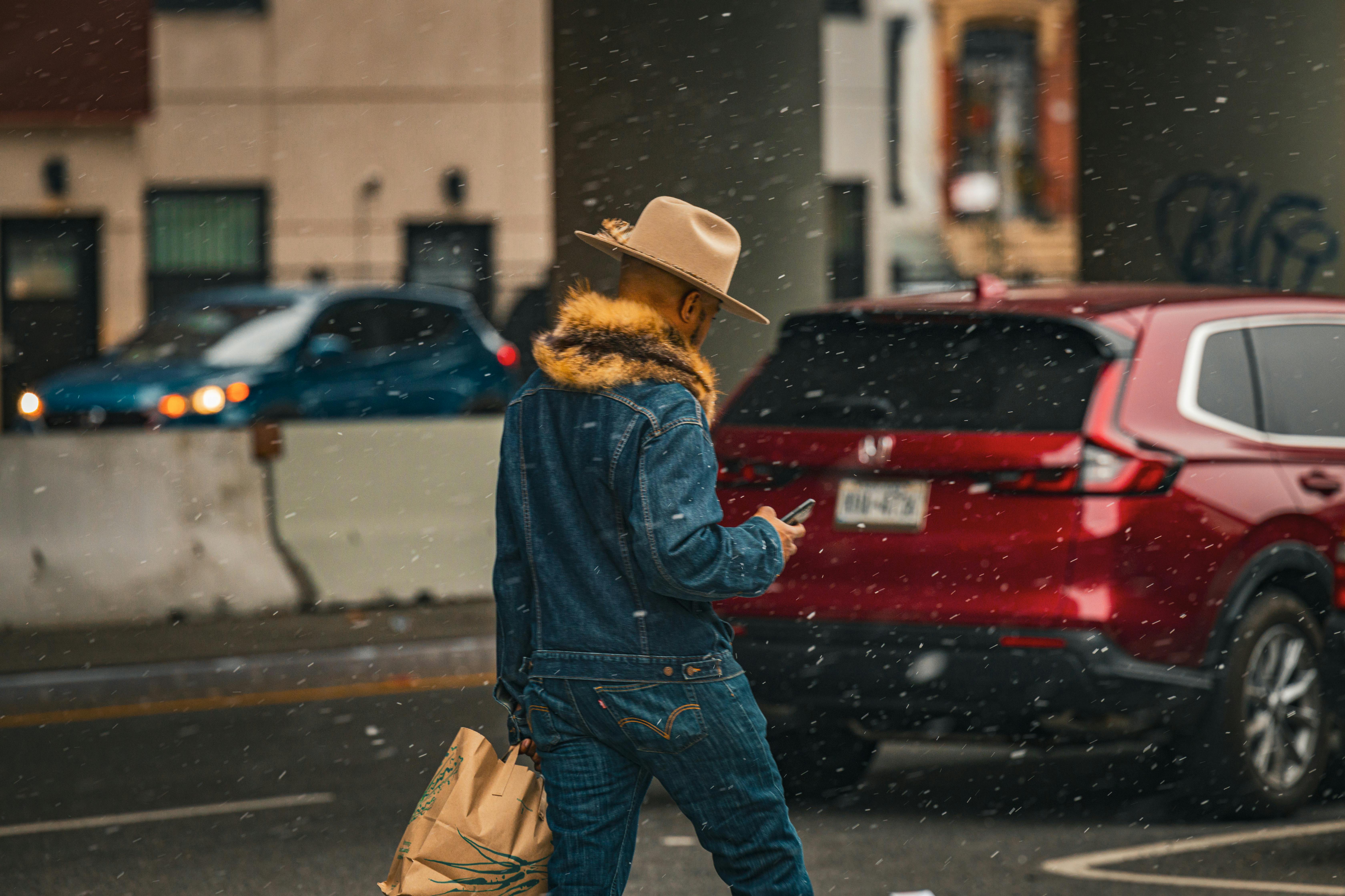 Candid shot of a man in cowboy attire walking in snowy New York street.