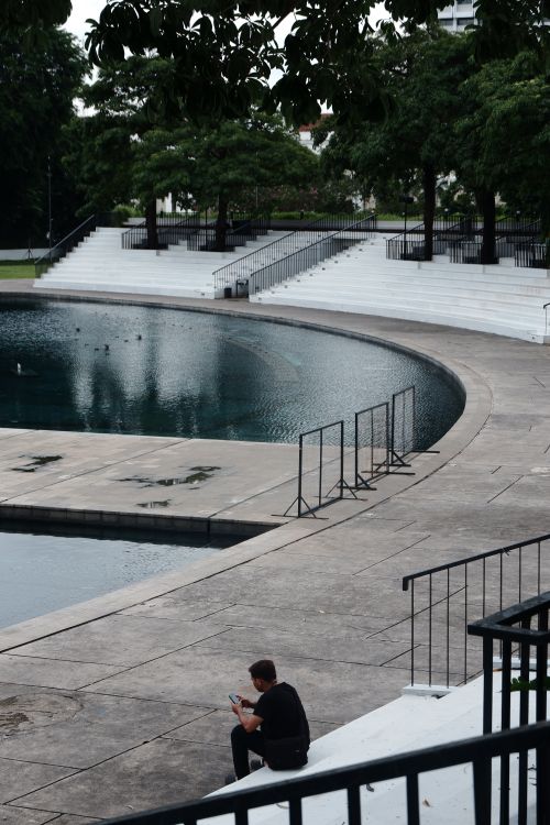 Free A tranquil urban park in Jakarta with a curved pond and seating, perfect for relaxation. Stock Photo