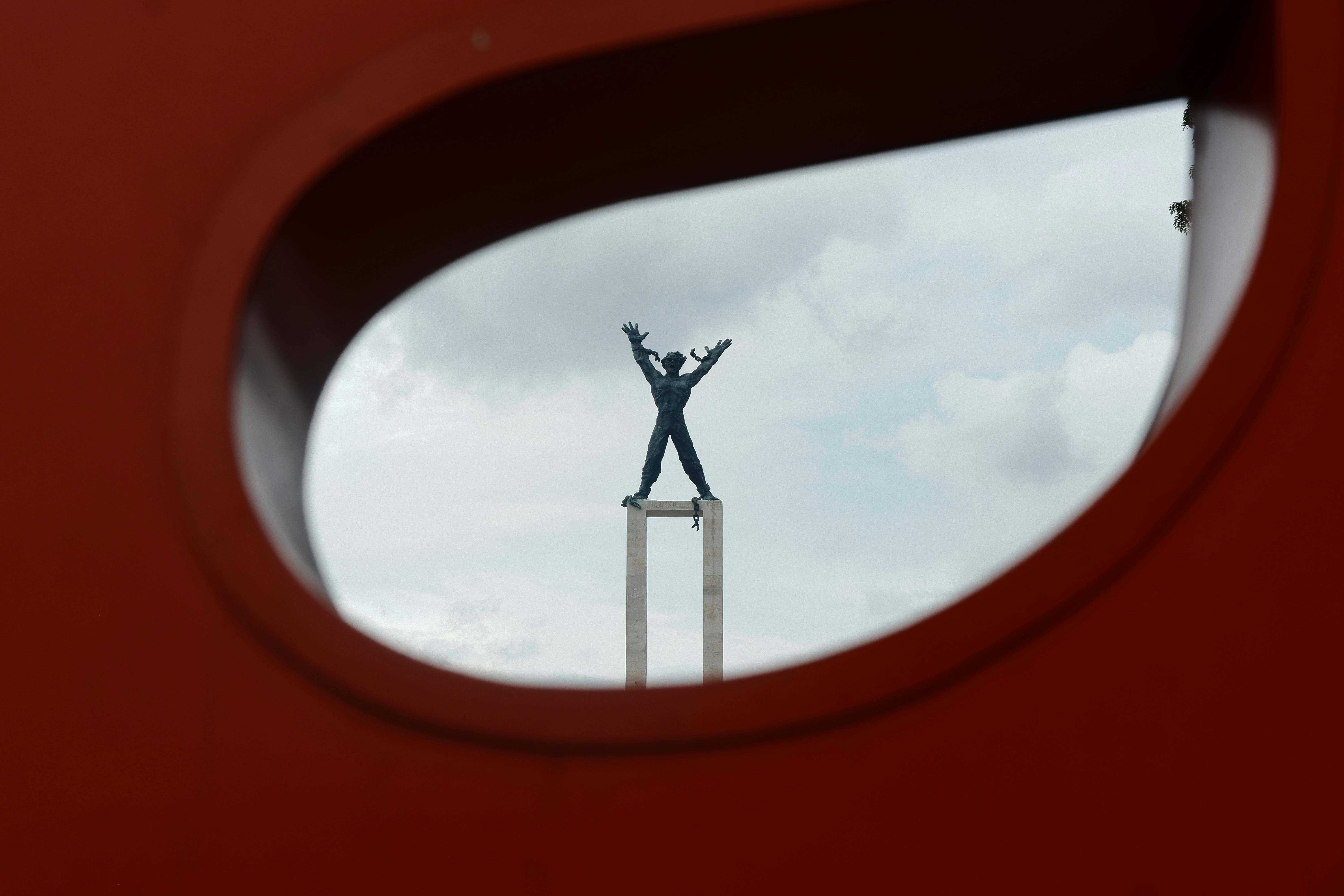 grátis Vista artística do Monumento da Proclamação de Jacarta emoldurado por uma escultura vermelha, demonstrando criatividade. Foto profissional