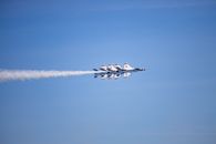 The US Air Force Thunderbirds perform precision flying at an air show under clear blue skies.