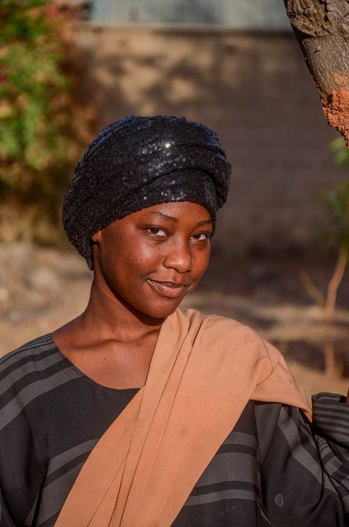 Free A woman in traditional clothing smiling softly against an outdoor backdrop. Stock Photo