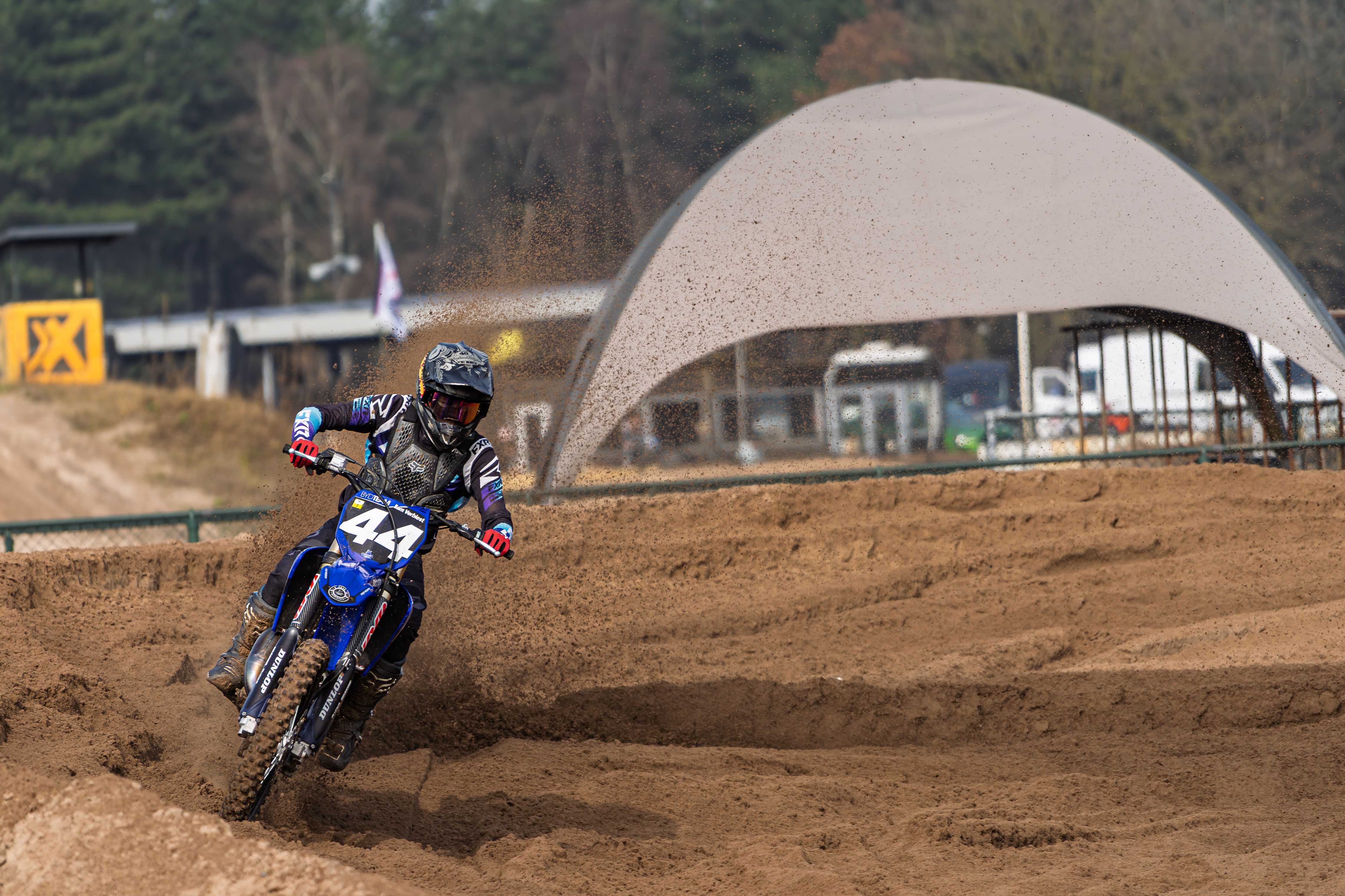 Dynamic shot of a motocross rider speeding through a sandy track during the day, showcasing action and excitement.