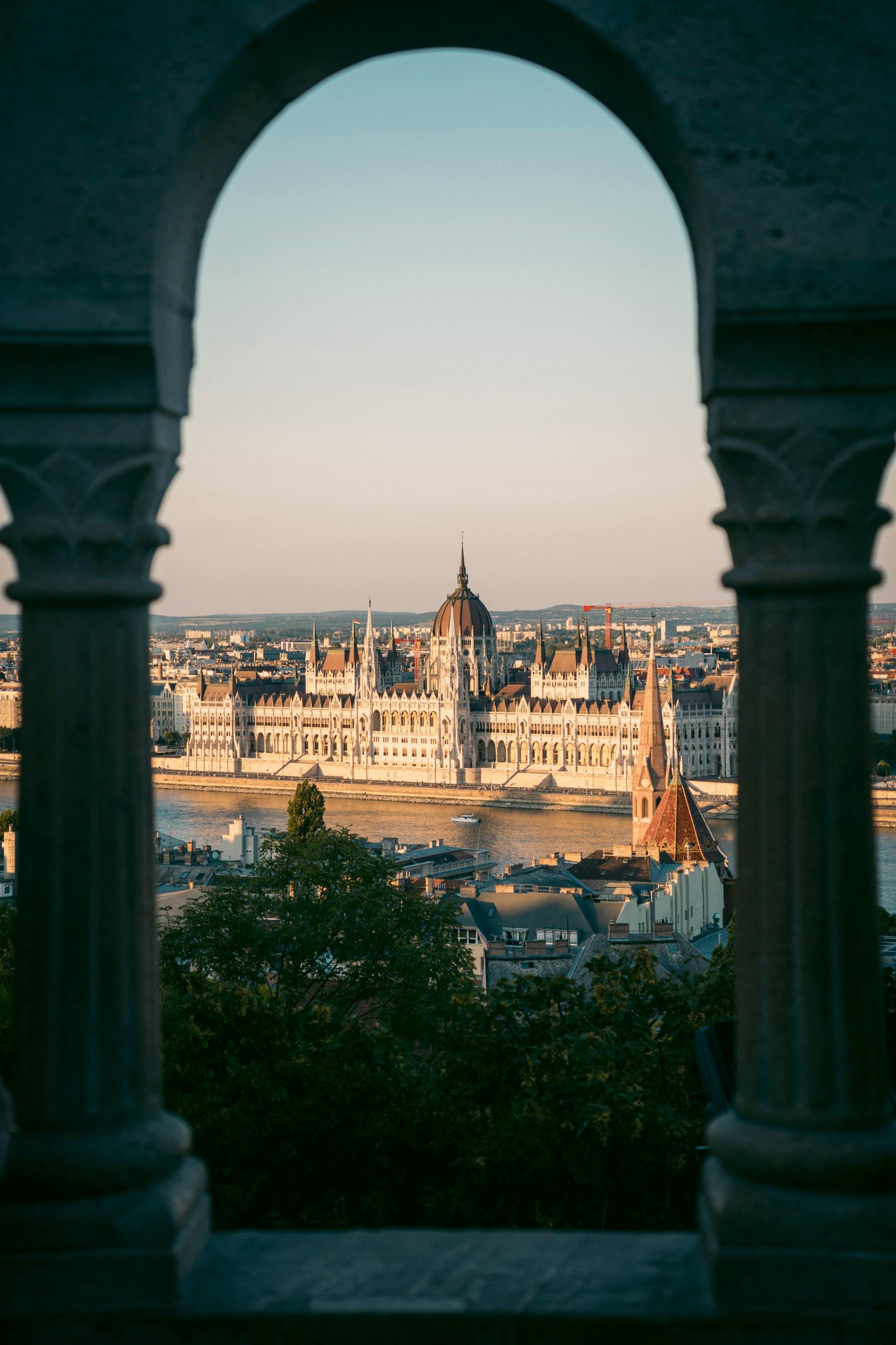 Stunning view of the Hungarian Parliament in Budapest framed by architectural arches.
