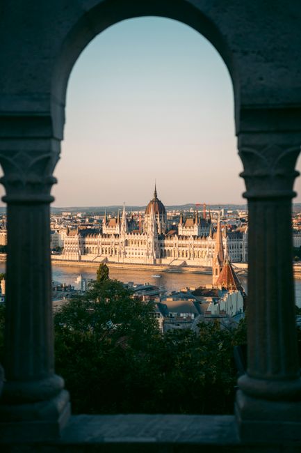 Stunning view of the Hungarian Parliament in Budapest framed by architectural arches.