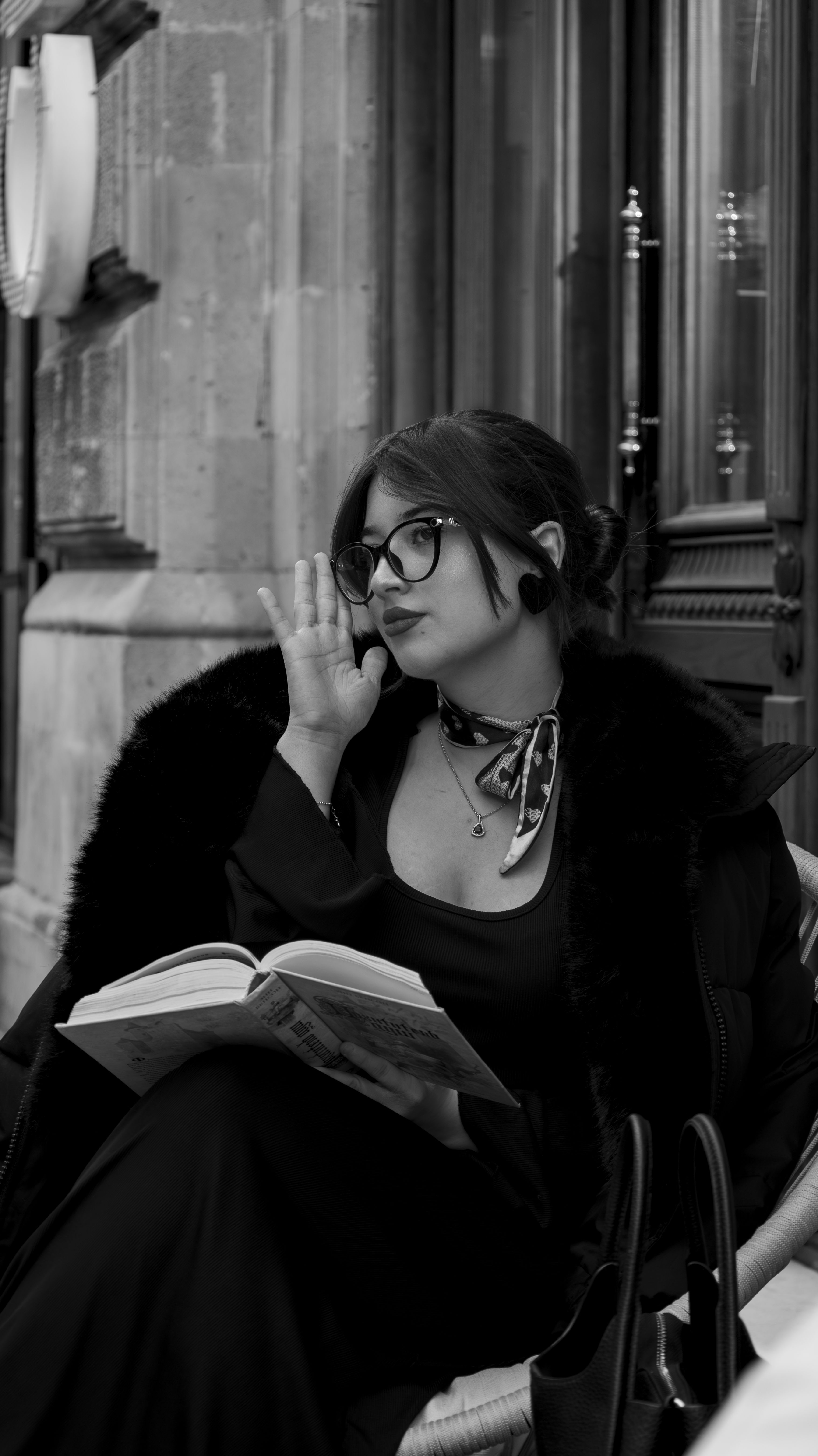 Stylish woman in black fur coat reading a book on a street in Baku, Azerbaijan.