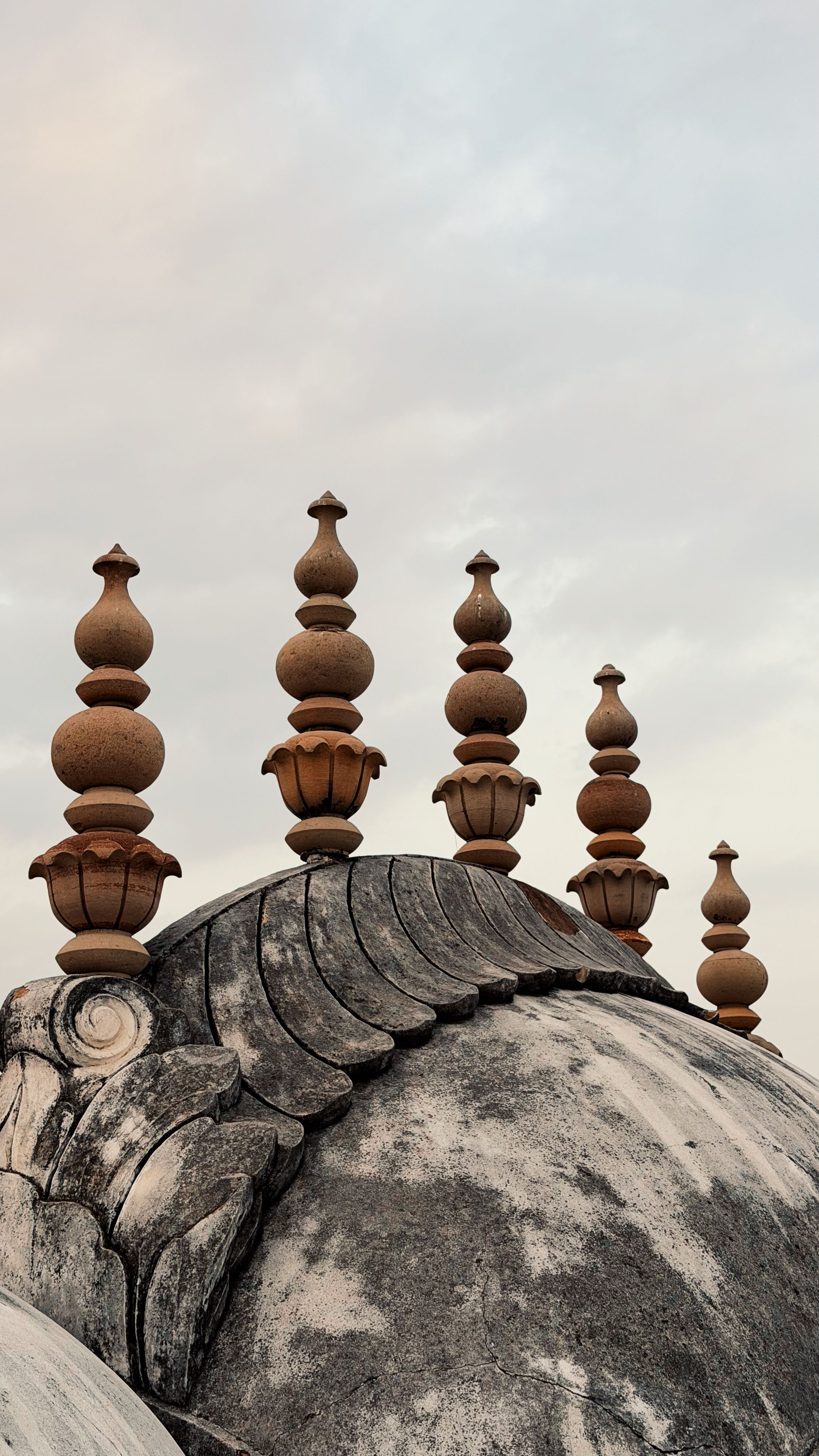 Intricate architecture of dome with ornate spire details against a soft sky.