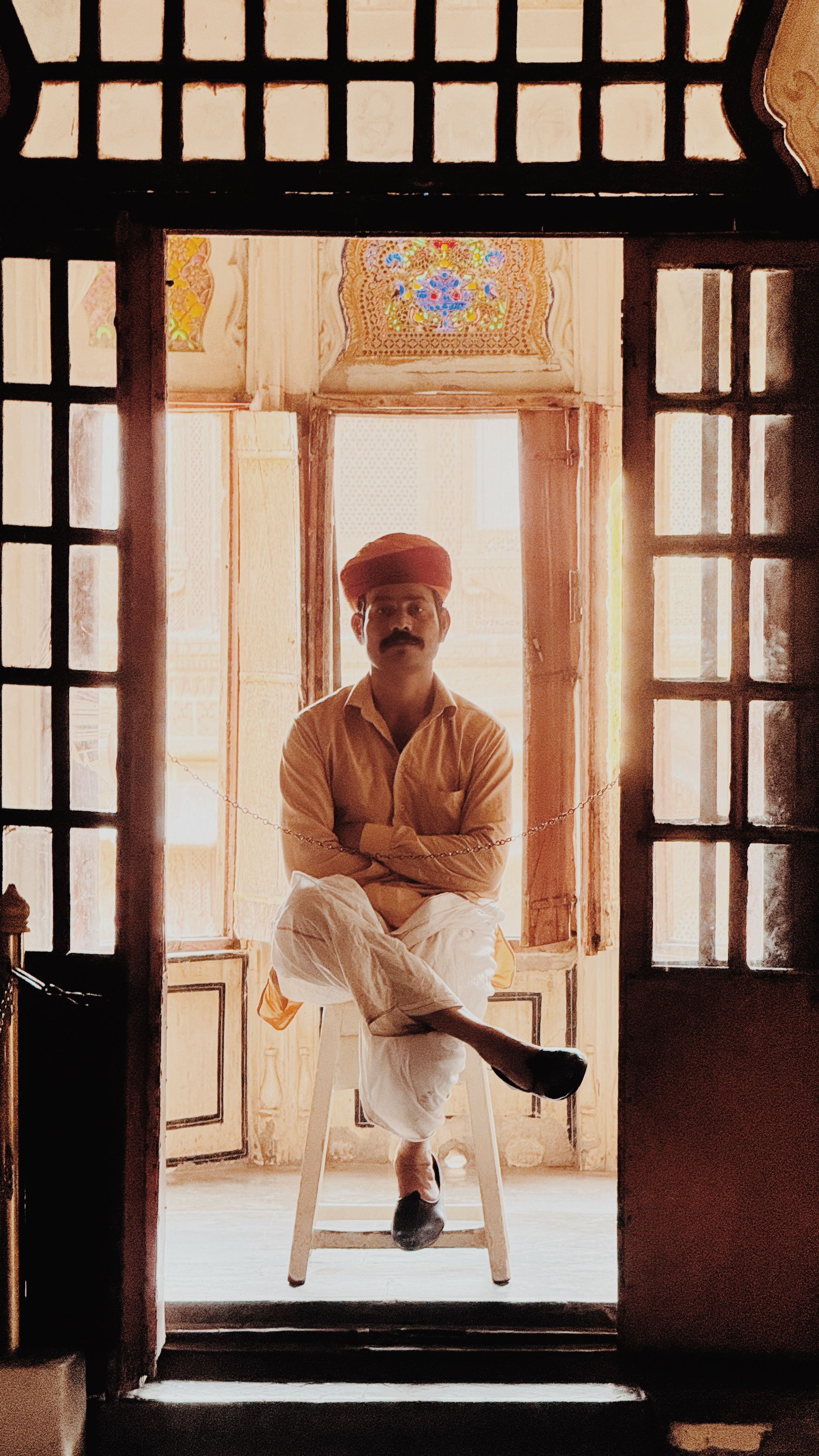 A Rajasthani man wearing traditional attire sits inside a historic building in Jodhpur, India.