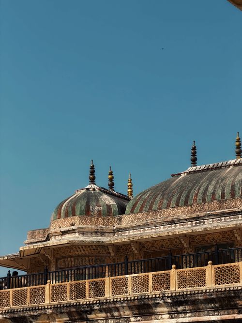 Free Detailed view of a historic Indian palace with ornate domes under a bright blue sky. Stock Photo