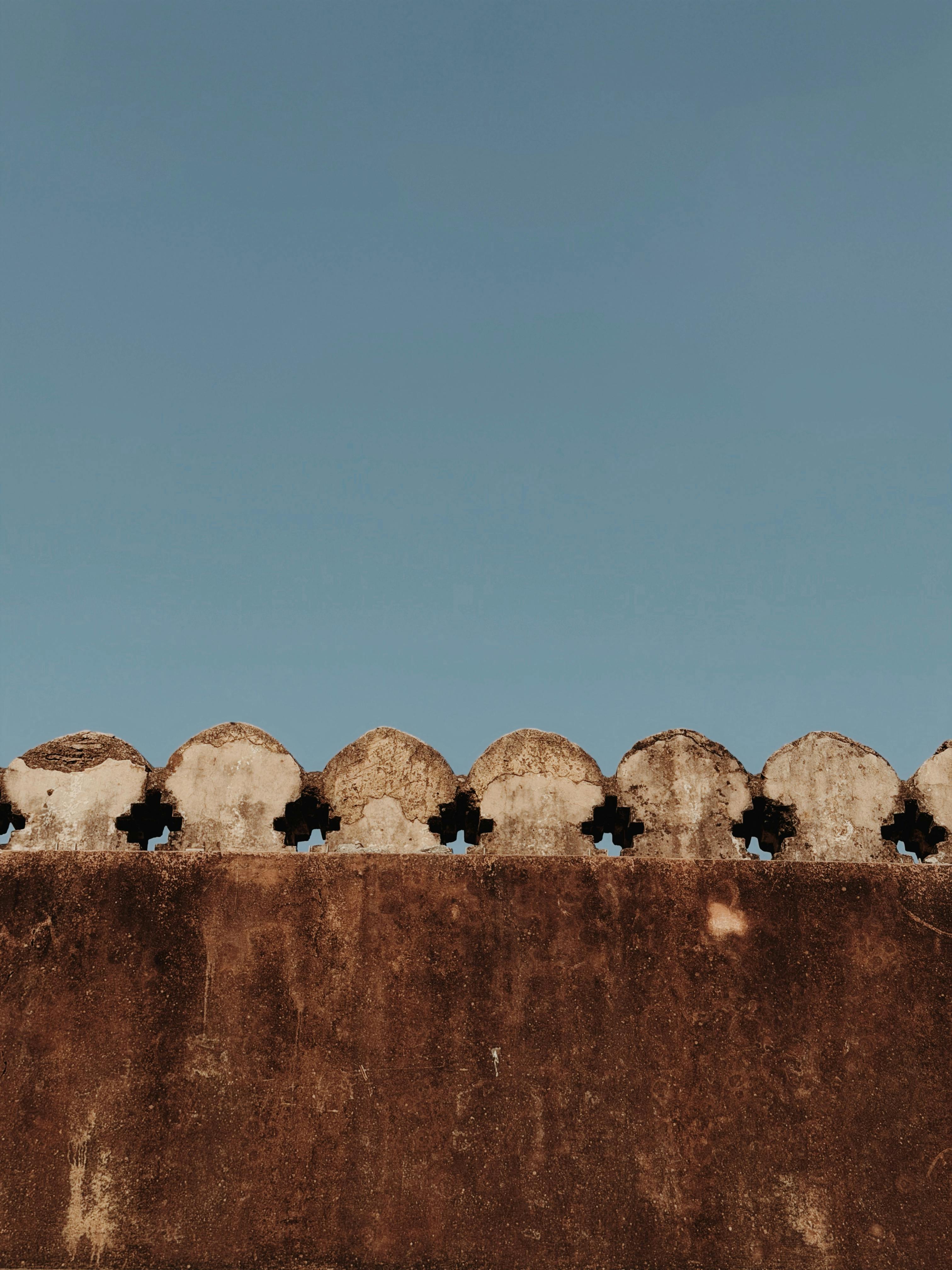 Free Rustic historic wall under a clear blue sky, showcasing weathered textures and architectural details. Stock Photo