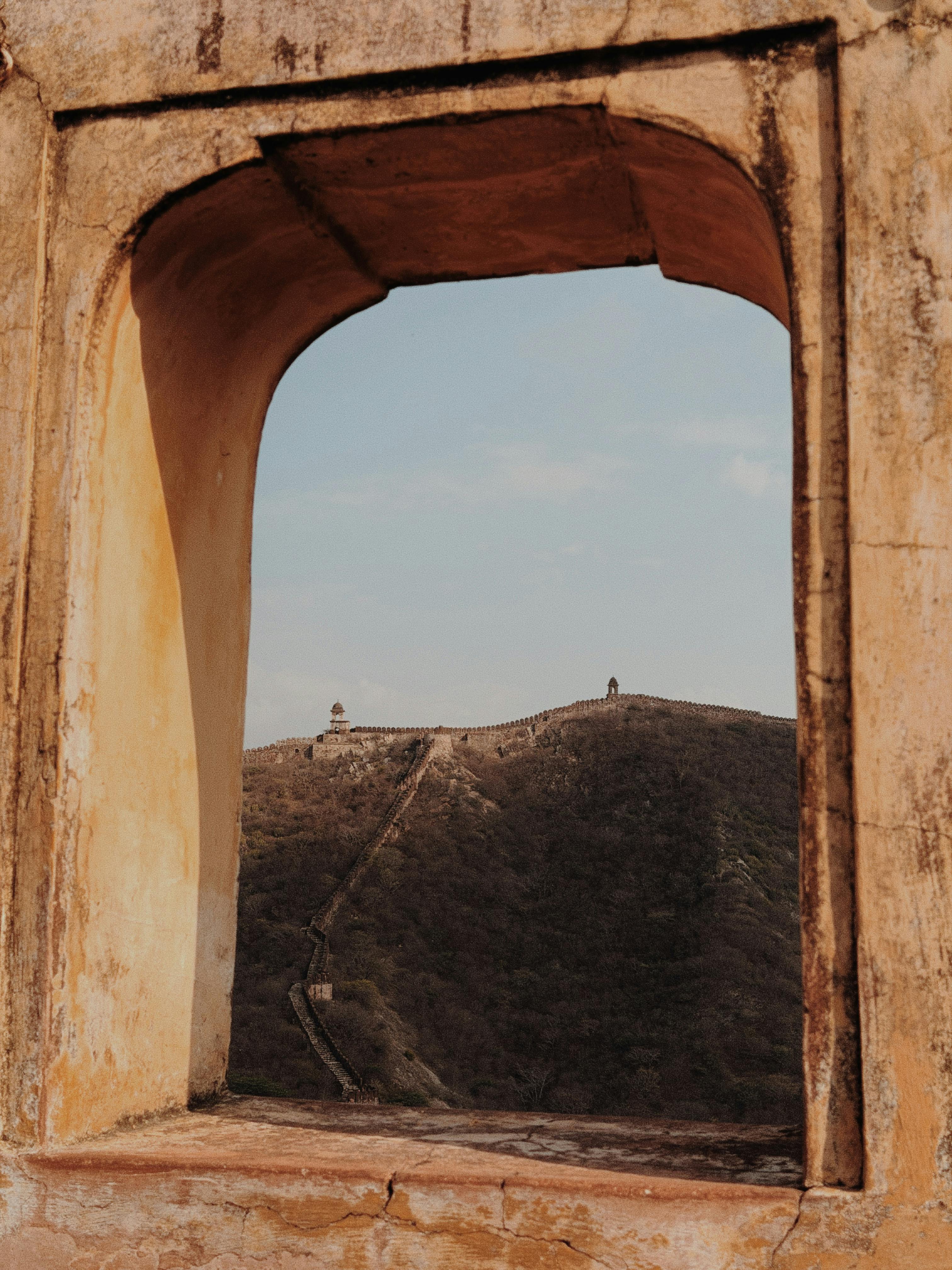 Gratuit O priveliște pitorească printr-o fereastră antică, prezentând un zid istoric din India sub un cer senin. Fotografie de stoc