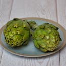 蓝色盘子里盛着两个新鲜的洋蓟，非常适合健康烹饪和美食摄影