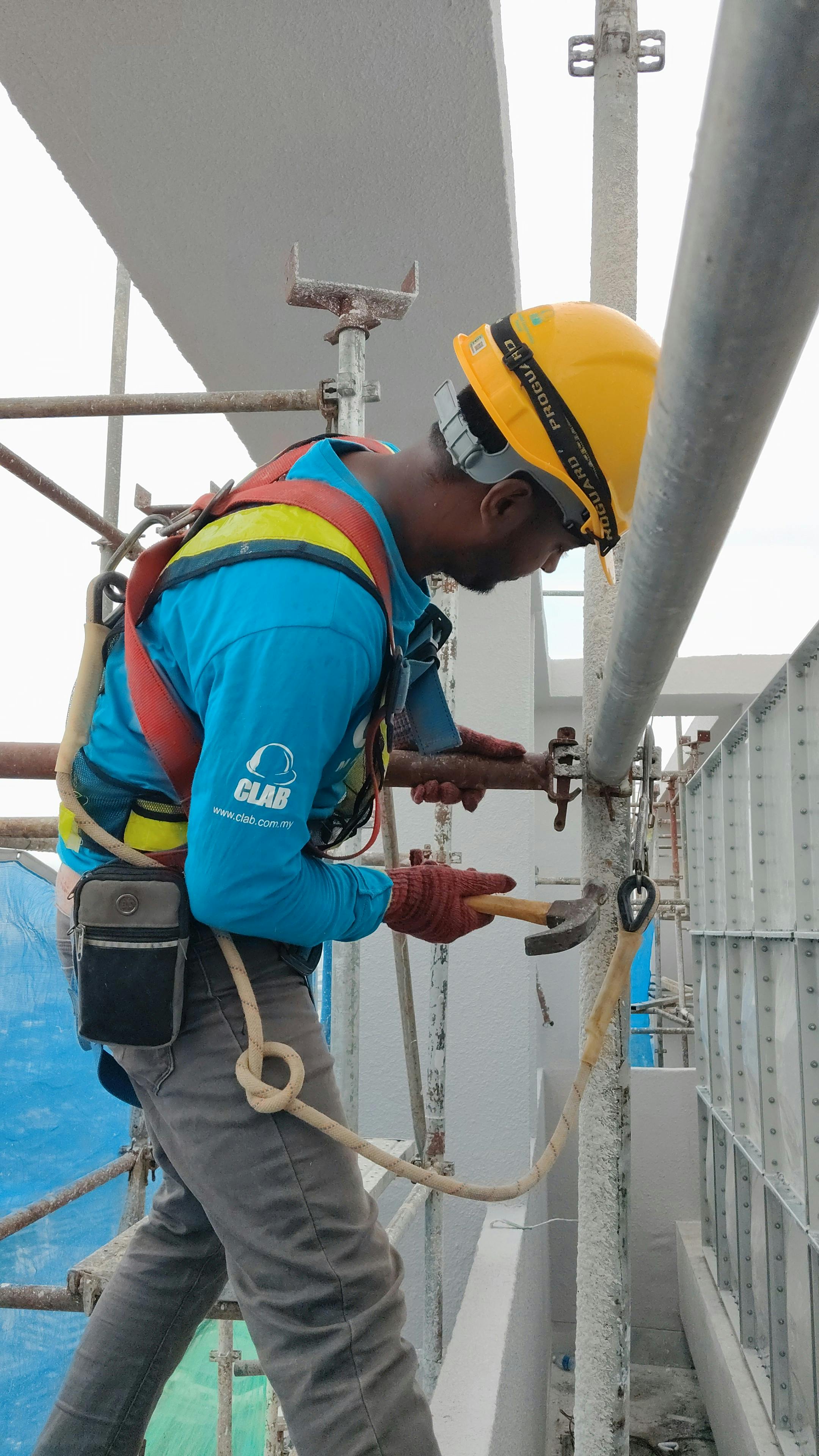 A construction worker wearing safety gear working on scaffolding at a building in Dubai.