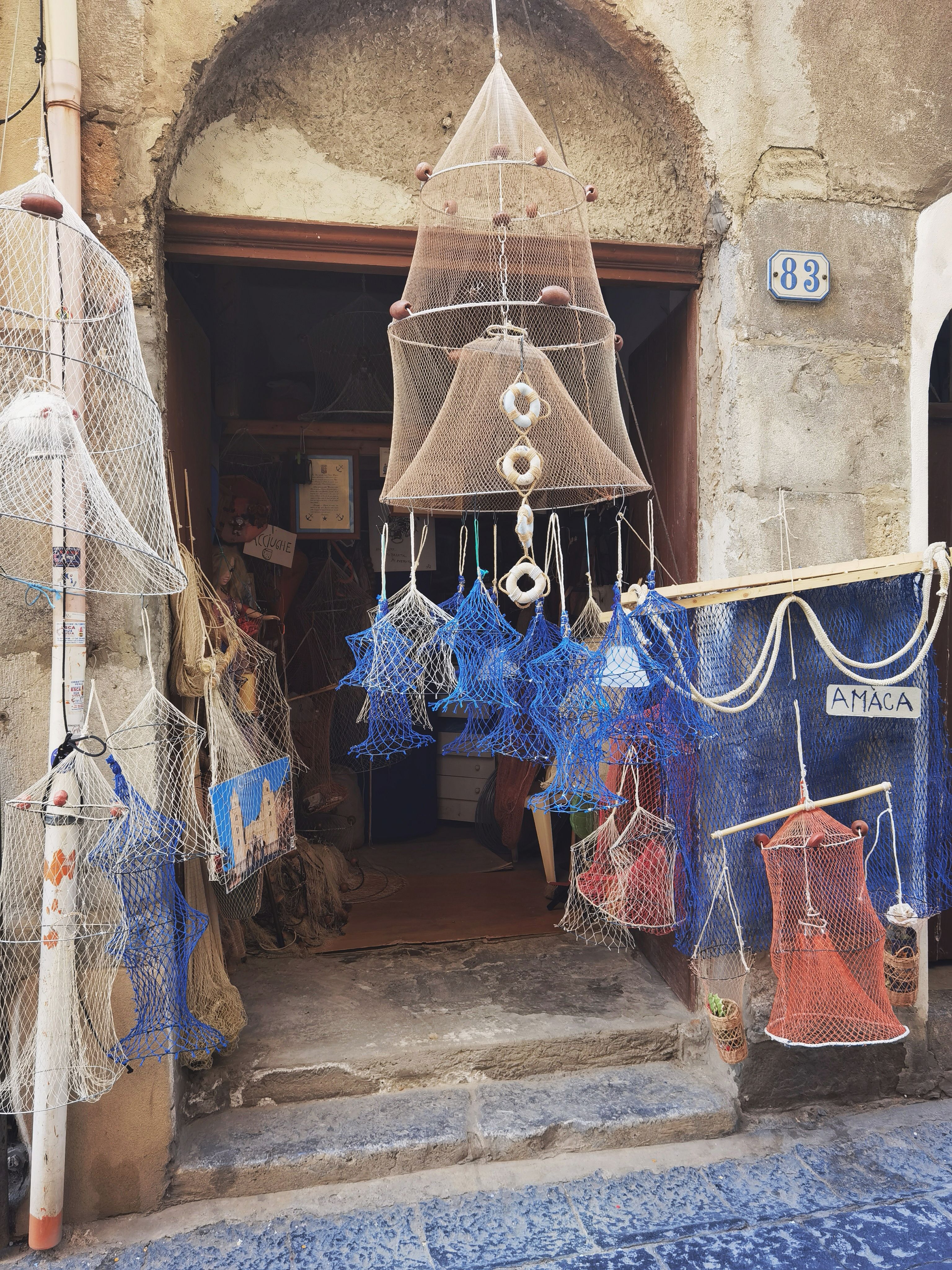 Charming shop displaying handmade nets and lanterns, conveying a rustic ambiance on a cobblestone street.