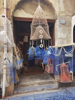 Charming shop displaying handmade nets and lanterns, conveying a rustic ambiance on a cobblestone street.