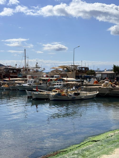 Free Scenic view of boats docked in a sunny harbor with blue skies and fluffy clouds in Kas, Turkey. Stock Photo