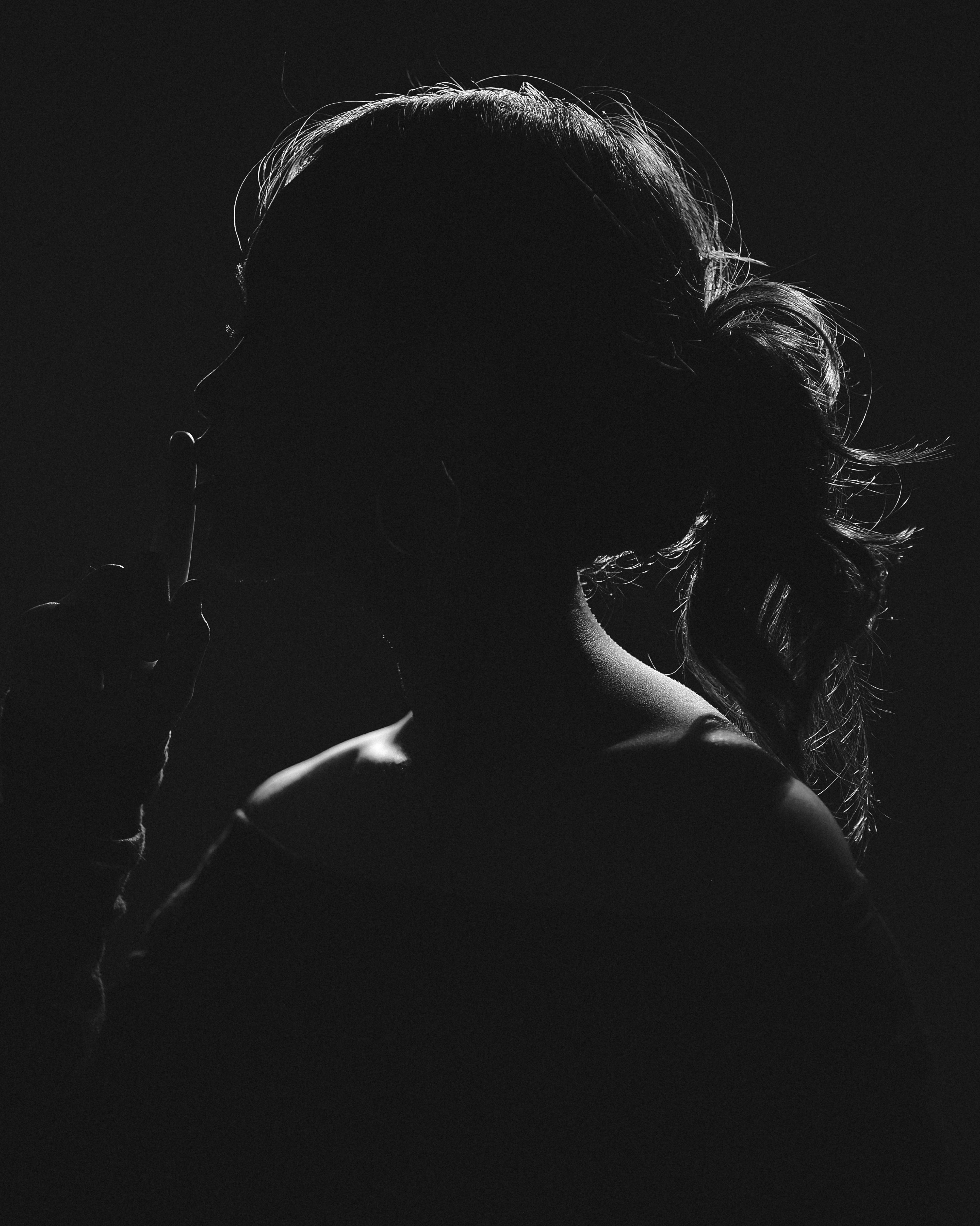 gratis Artistiek silhouet van een vrouw met een vinger op haar lippen, wat geheimzinnigheid suggereert. Stockfoto