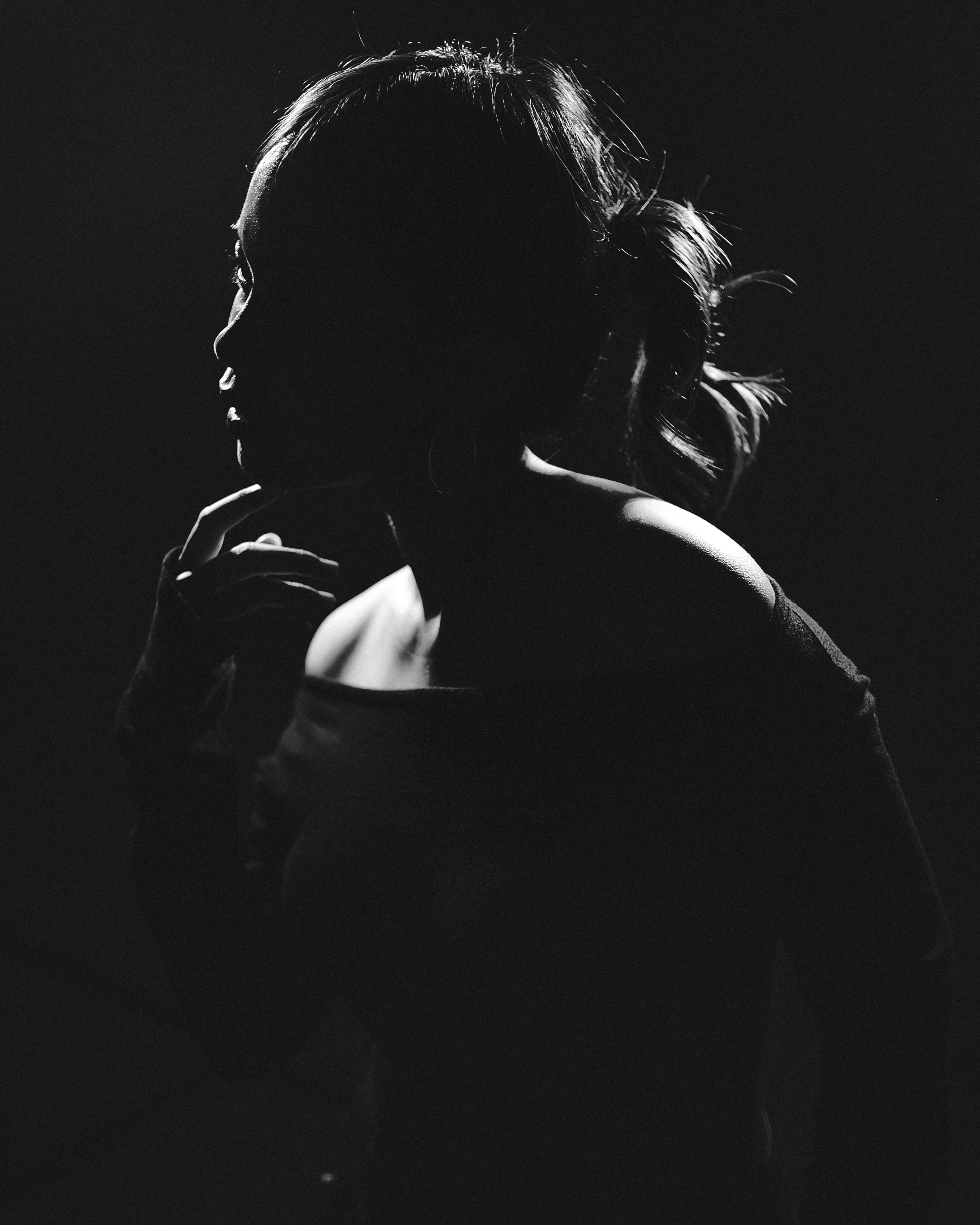 Gratuit Silhouette en noir et blanc d'une femme, éclairée de façon dramatique pour créer une ambiance mystérieuse. Photos