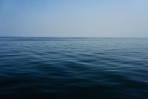 Free A serene view of the calm ocean surface stretching into the horizon at Musandam, Oman. Stock Photo