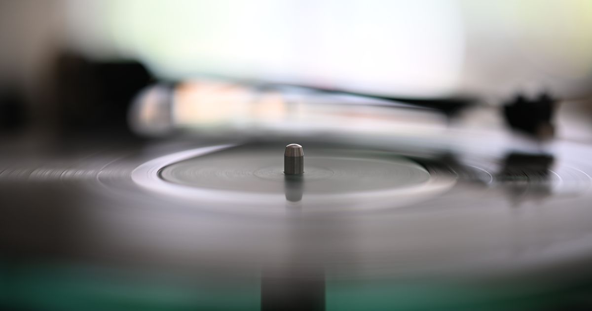 Blurry spinning vinyl record with needle on turntable, capturing the essence of analog music.