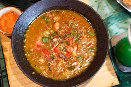 Delicious Indonesian Sop Buntut served with spicy sambal on a wooden table.