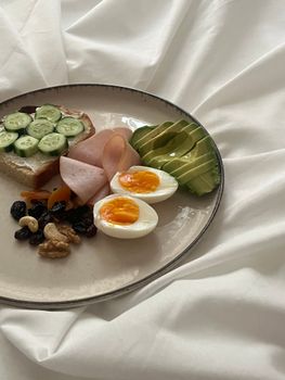 Delicious breakfast featuring avocado, eggs, nuts, and cucumber toast.