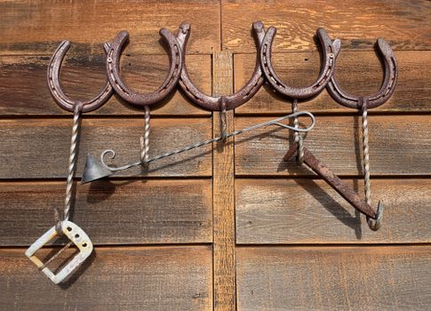 A rustic display of horseshoes and tools on a wooden barn wall in California, USA.