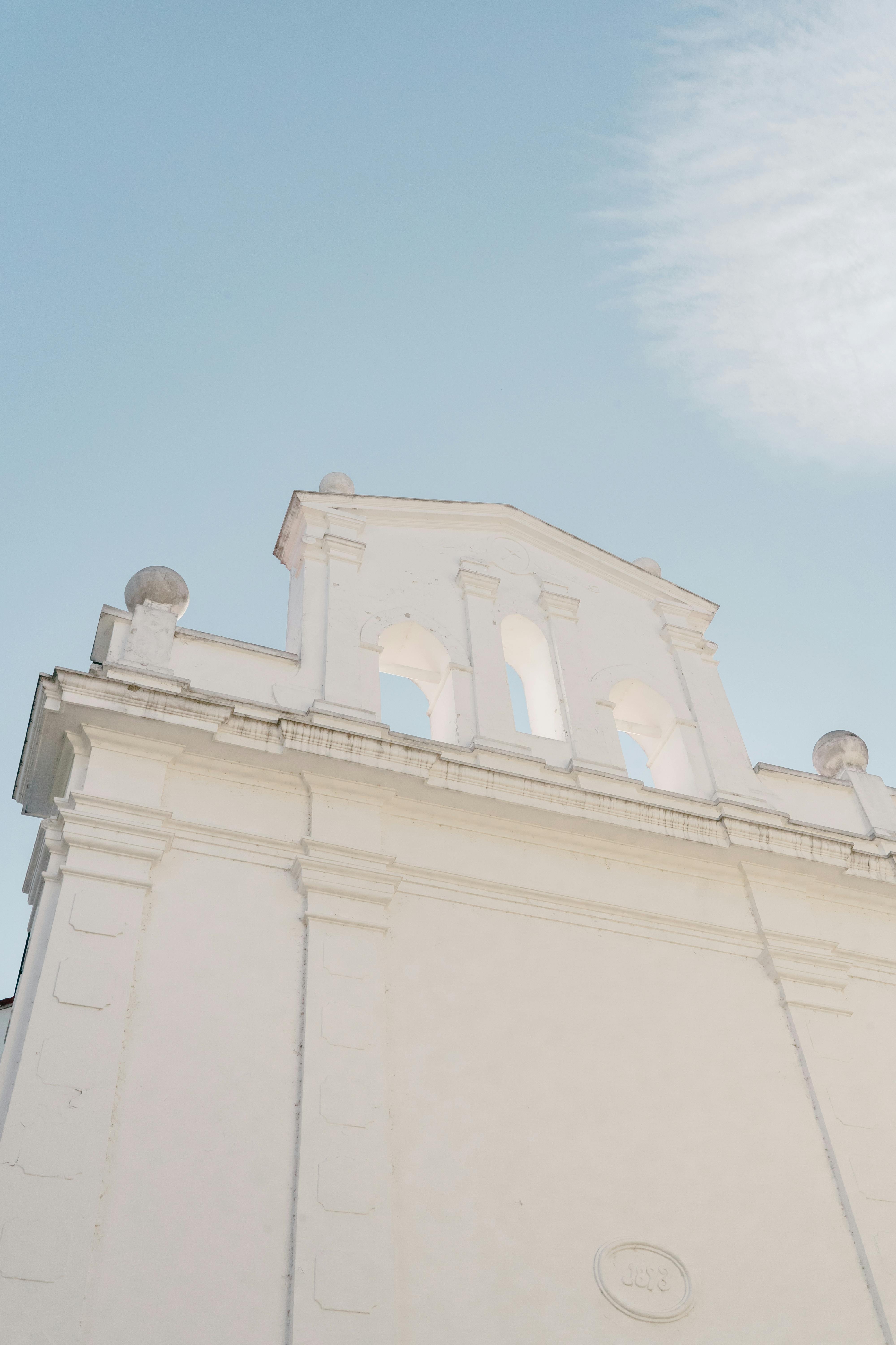 Gratuit Fotografie minimalistă a unei fațade albe a unei clădiri istorice, cu cer albastru senin și lumină solară blândă. Fotografie de stoc