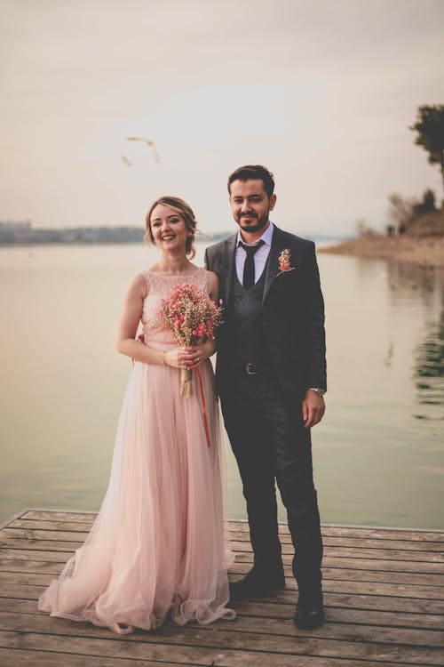 Uomo In Abito Nero In Piedi Accanto A Donna In Abito Rosa Azienda Bouquet Di Fiori