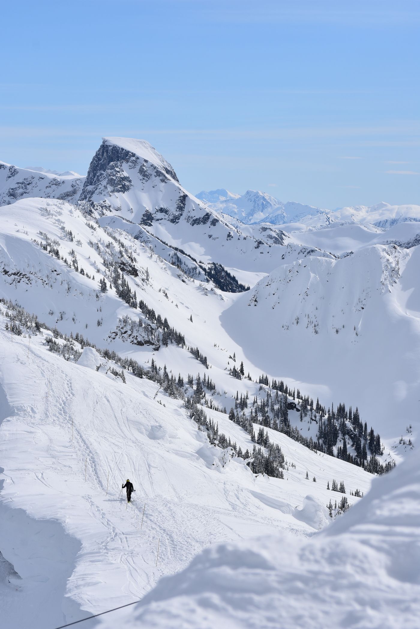 A skier descending a steep snow-covered slope in the mountains above Revelstoke, British Columbia