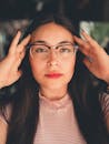一位年轻女子调整眼镜的肖像，带着自信的表情直视镜头