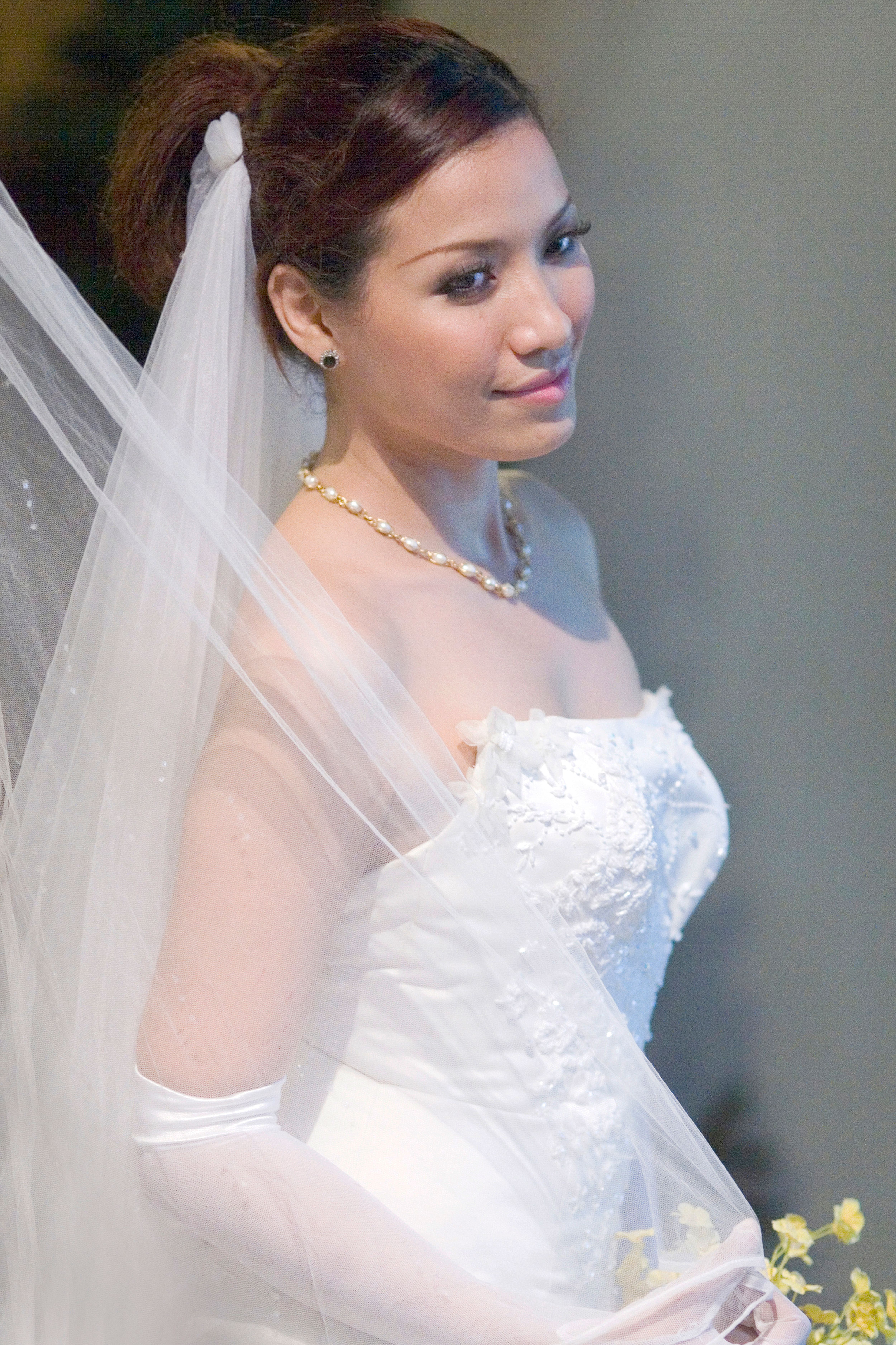 Beautiful bride in white lace dress and veil, looking serene and elegant.