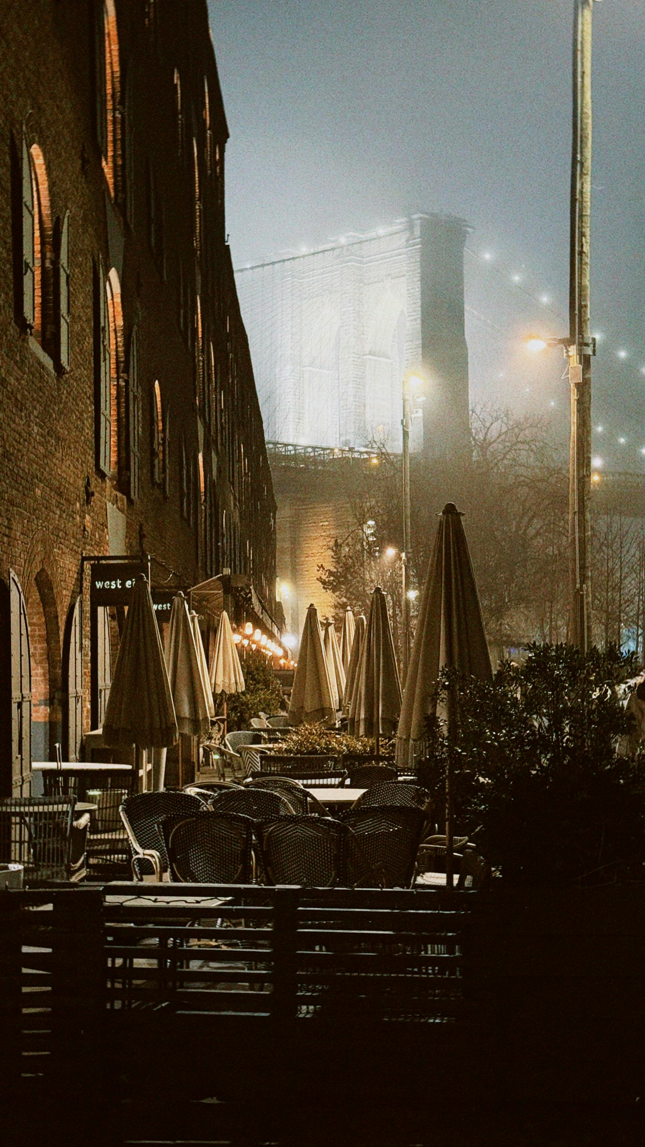 無料 ブルックリン橋の霧の夜景。屋外カフェと歴史的建築物が映っています。 写真素材