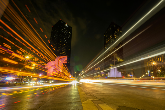 Dynamic light trails of night traffic in Mexico City, showcasing urban energy and architecture.