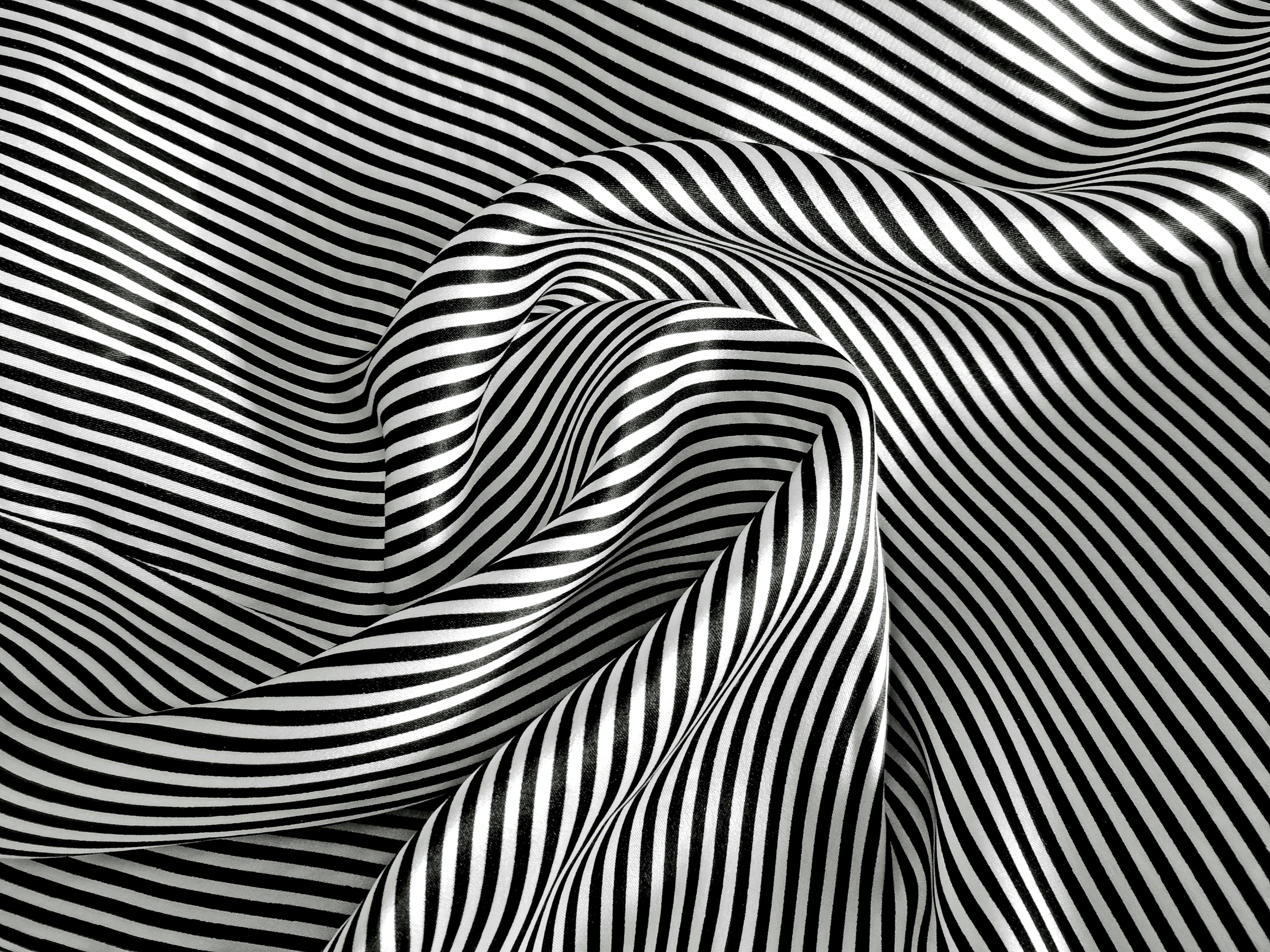 gratis De zwart-wit gestreepte stof creëert een abstract, betoverend patroon met rimpelingen en plooien. Stockfoto