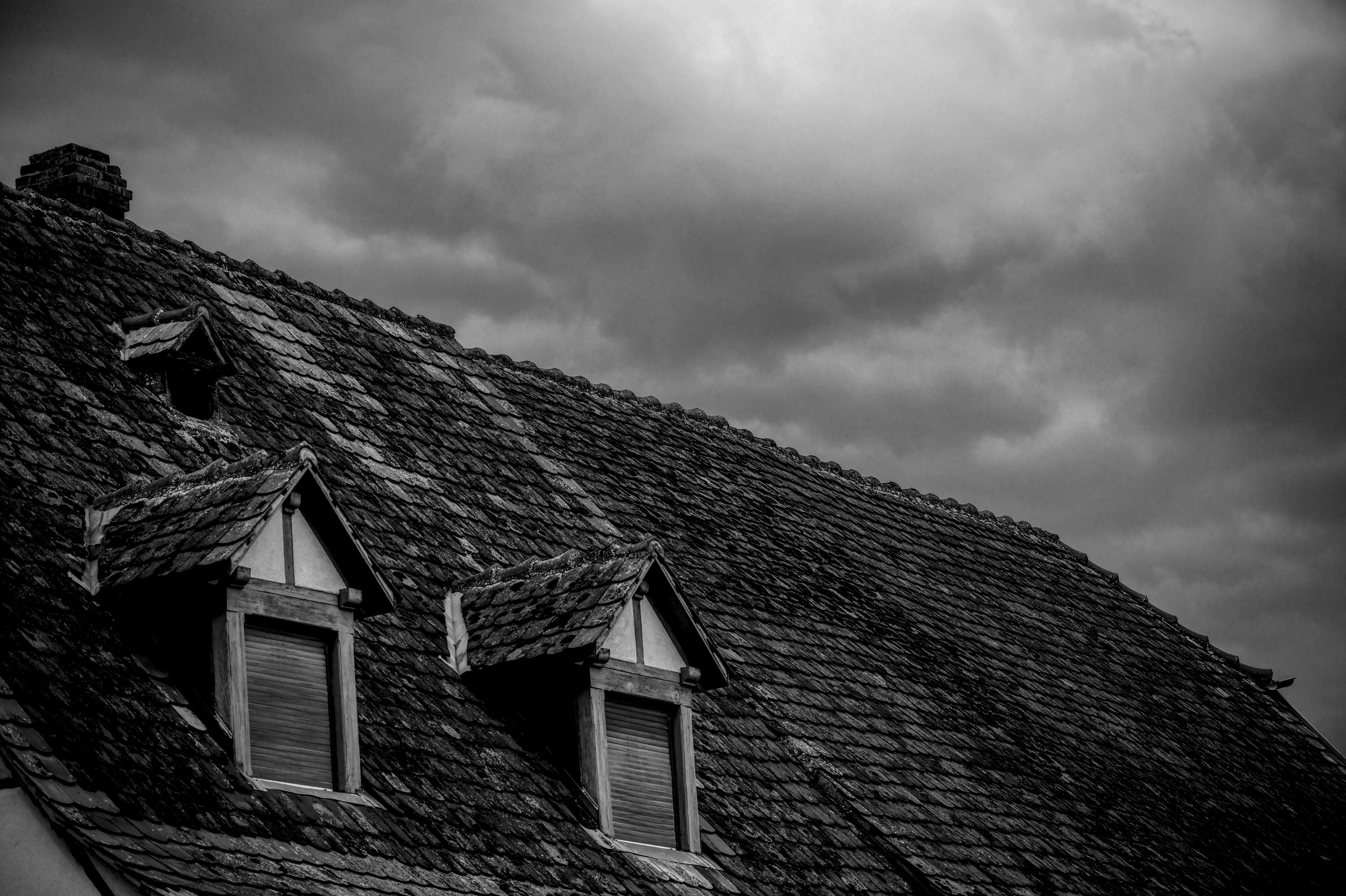 Gratis Una foto in bianco e nero di un tradizionale tetto di tegole sotto un cielo spettacolare, che emana un'atmosfera suggestiva e drammatica. Foto a disposizione