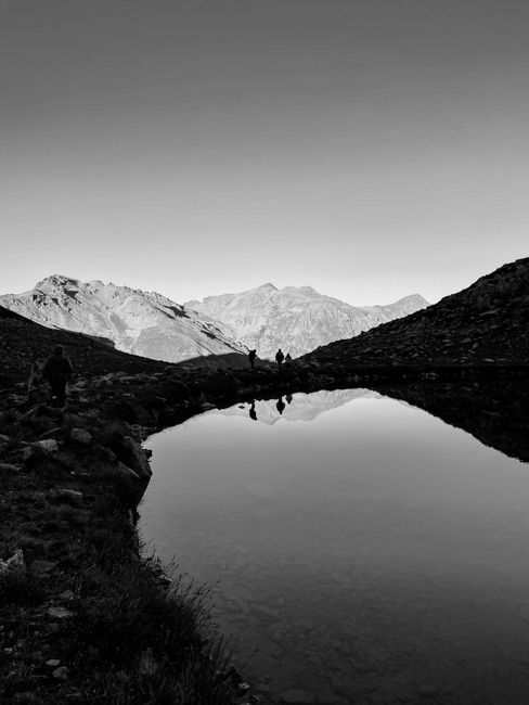 Serene black and white mountain reflection with silhouettes, capturing natural beauty.