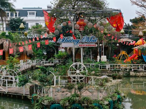 Outdoor view of a Vietnamese restaurant decorated with flags and plants.