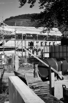 Monochrome image of a building under construction with scaffolding and equipment.