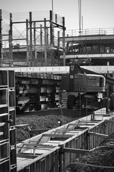 Monochrome image of a construction site featuring heavy machinery and scaffolding.