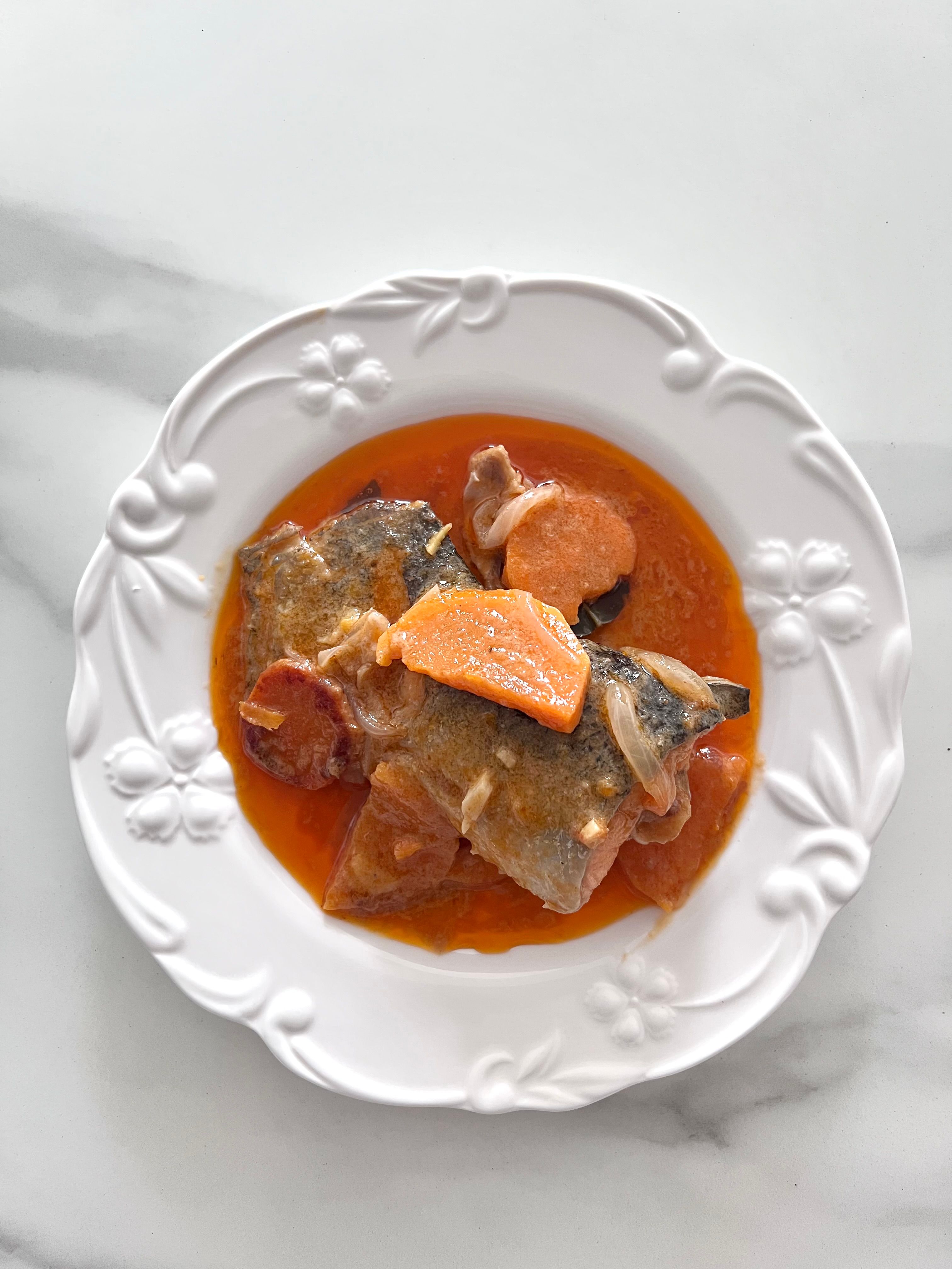 A vibrant fish stew on a decorative white plate. Perfect for culinary inspiration.